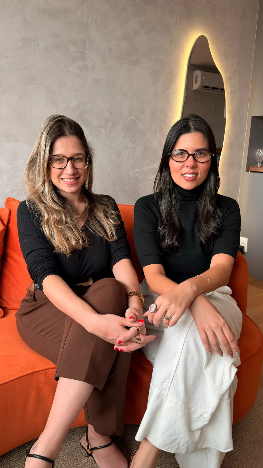 As advogadas Nathalia Louback e Gabriella Lopes sentadas lado a lado, olhando para a câmera.